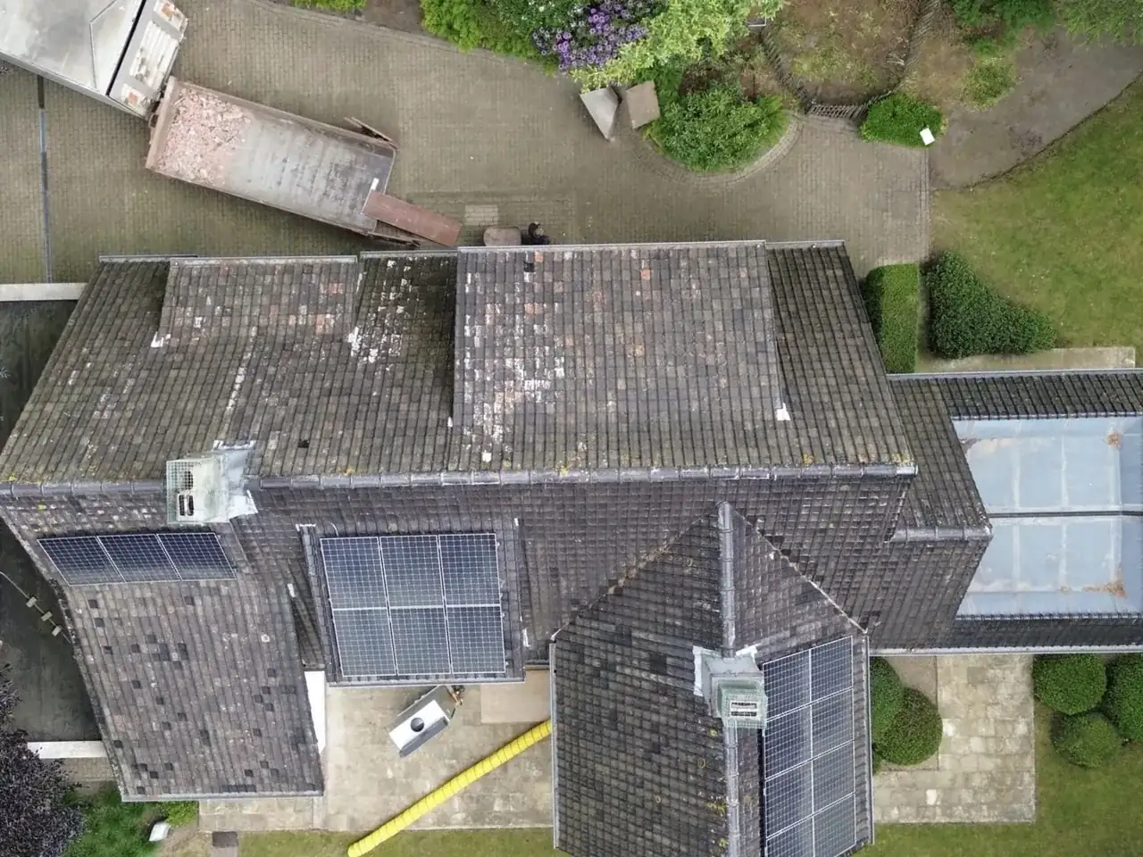 Luchtfoto van een vervuild dak met zonnepanelen voor dakreiniging