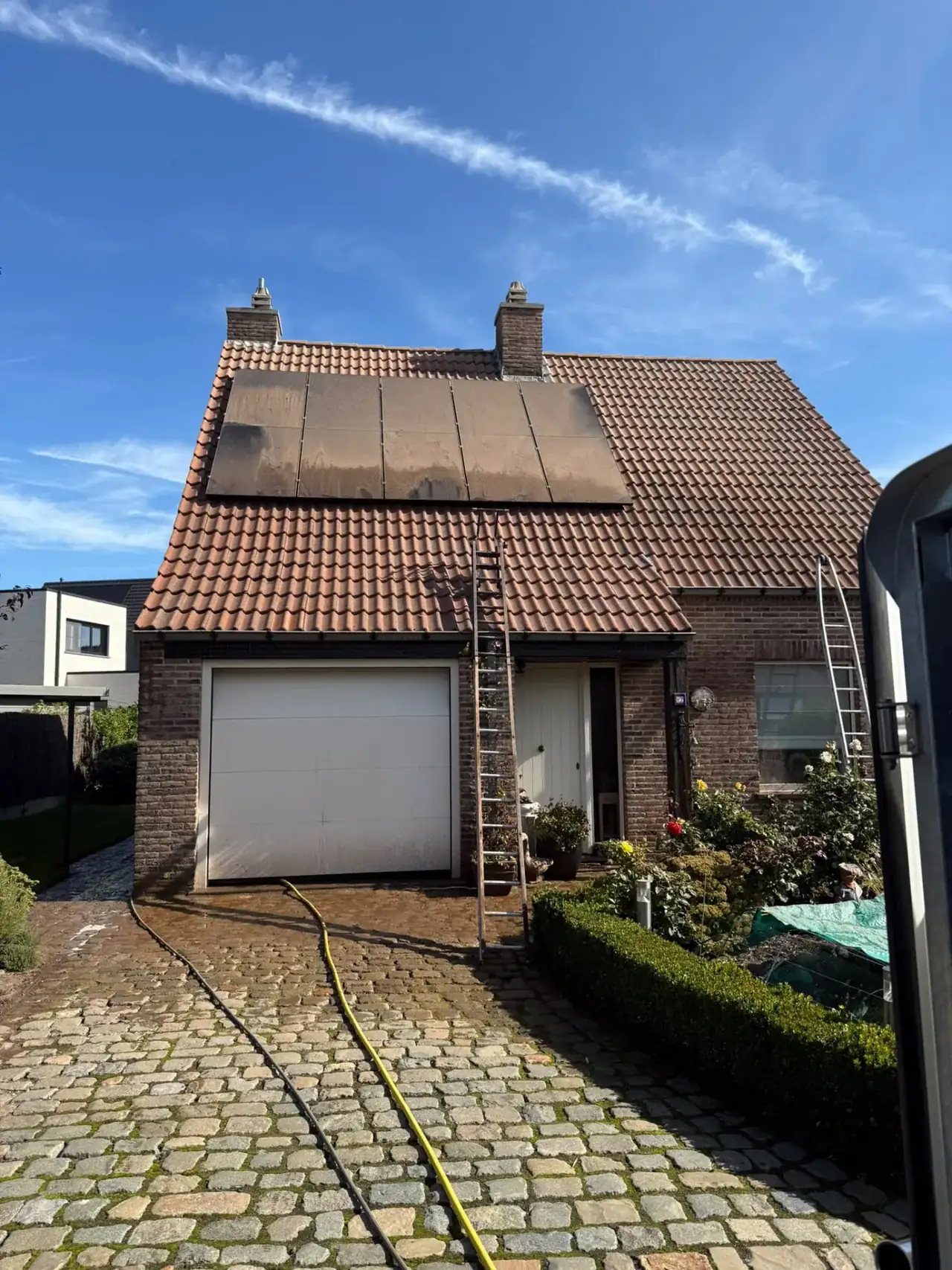 Dak met zonnepanelen en vervuilde pannen voor dakreiniging